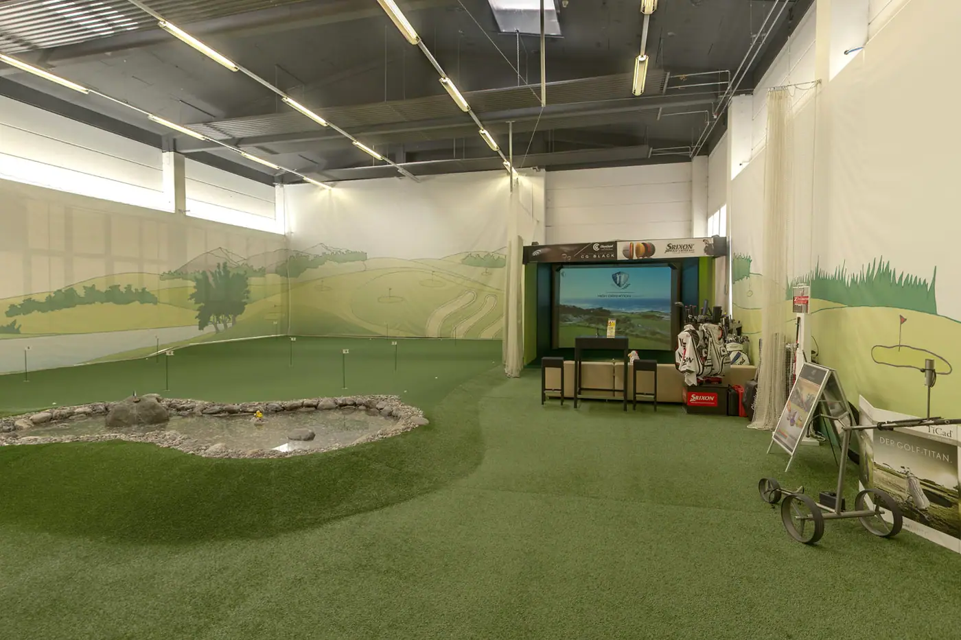 Simulator am Ende der Halle, davor Teich und Putting Green